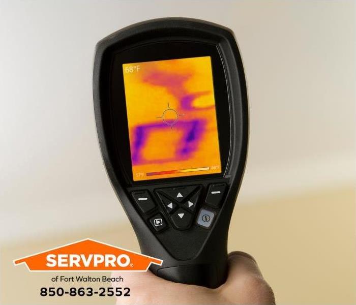 A technician uses an infrared camera to detect hidden water damage.